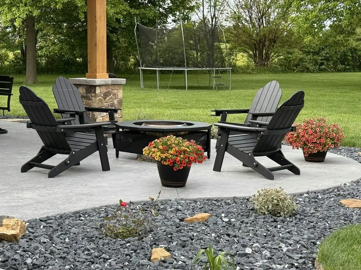 Concrete backyard patio with chairs around a fire pit
