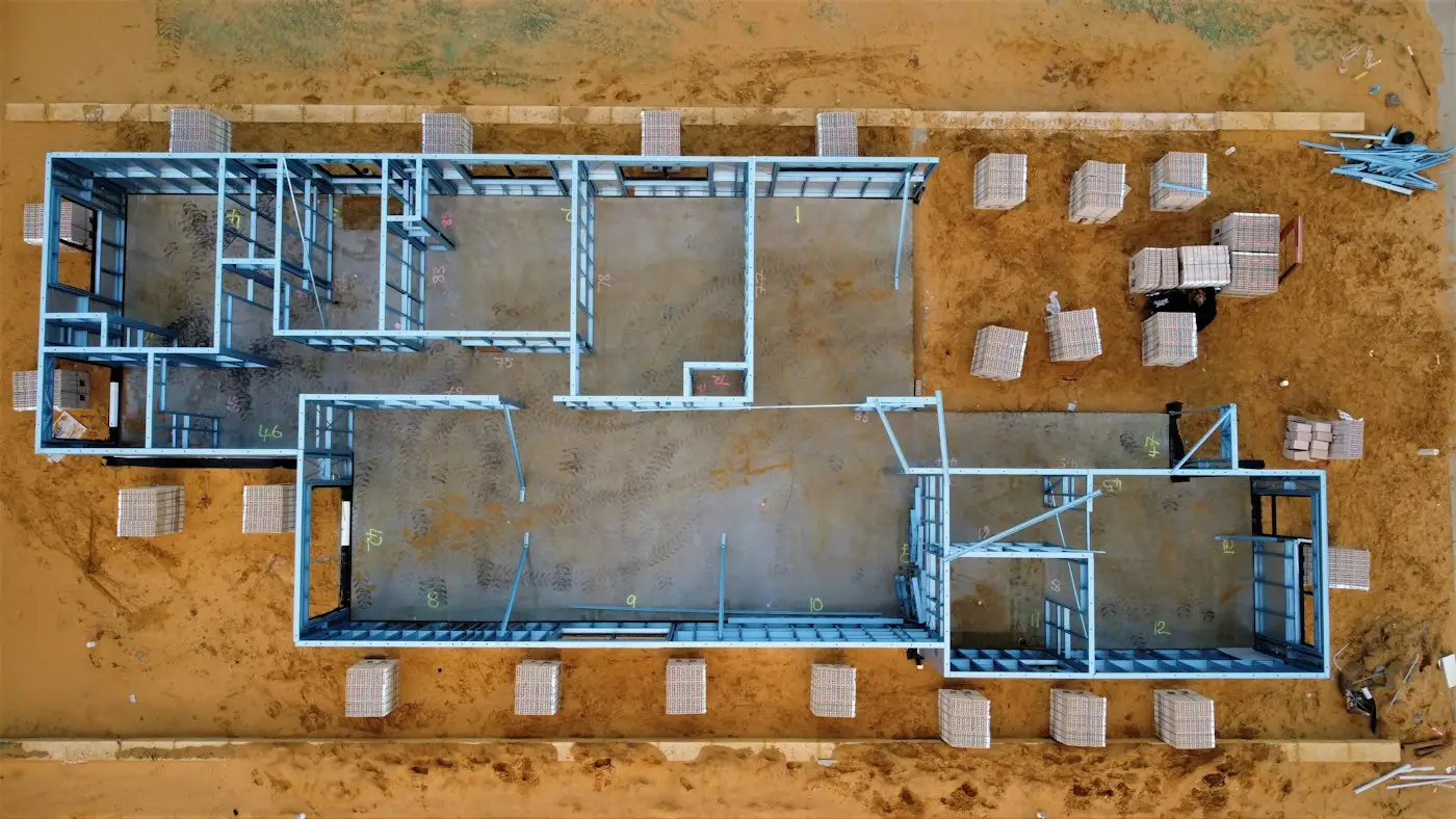Aerial view of a house slab with wall framing going up