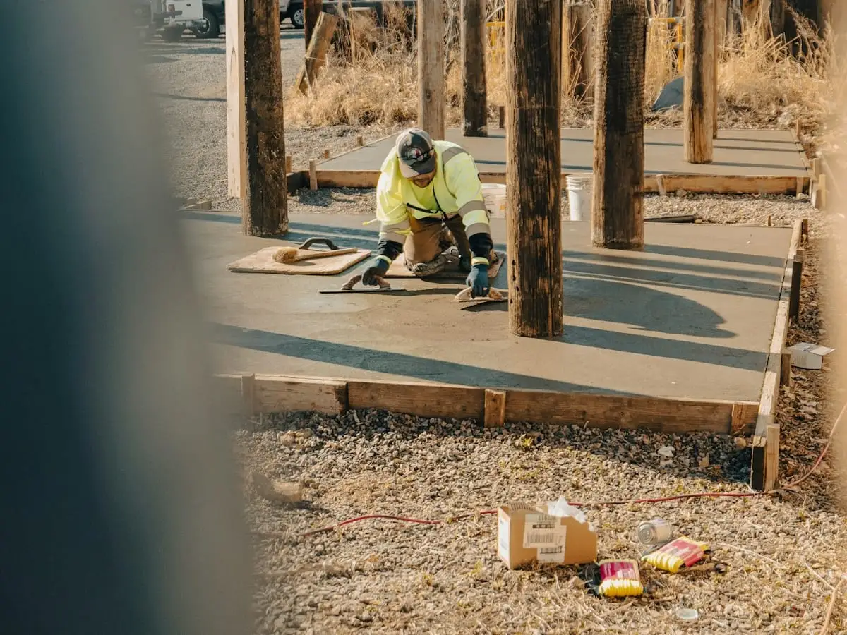 Worker finishing a fresh concrete slab inside wood forms